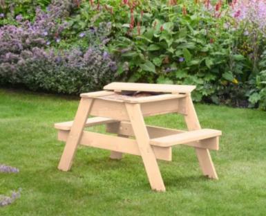 Beige children's sand table and picnic table in a garden.