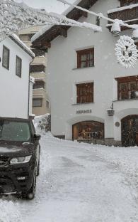 Black SUV parked in front of a snow-covered Hermès store.