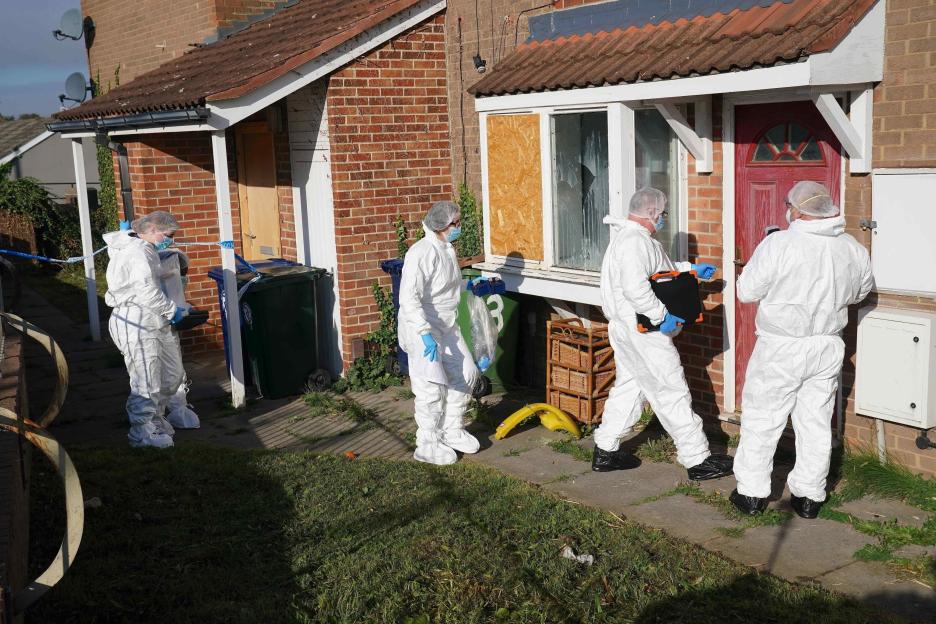 Crime scene officers in white suits investigating outside a residential home.