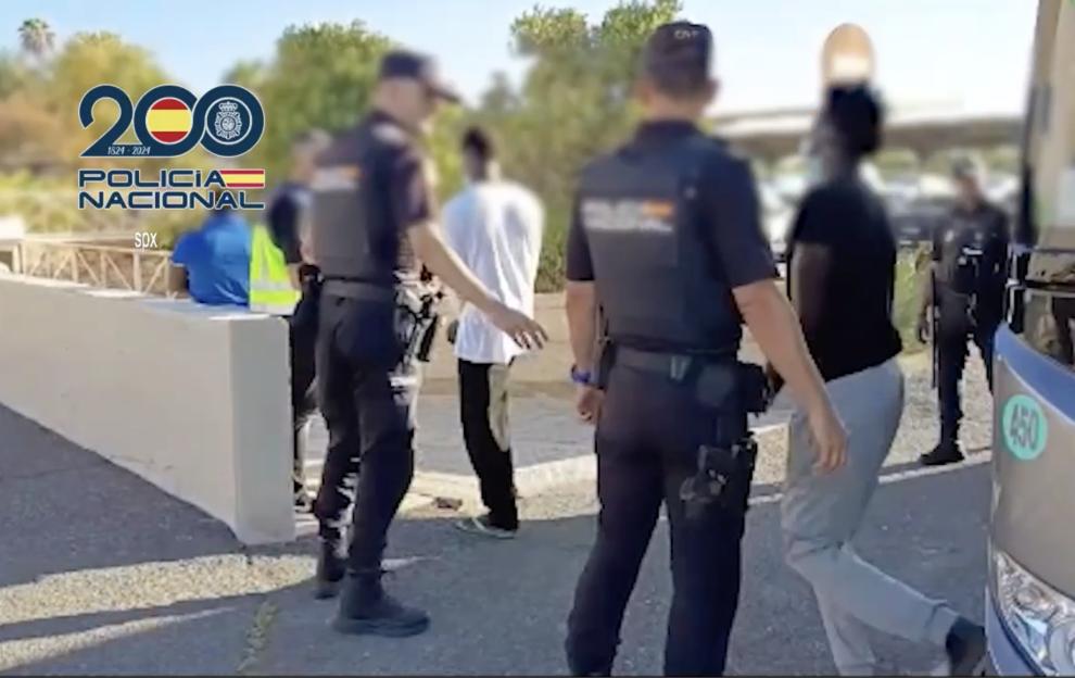 Police escorting migrants off a bus.