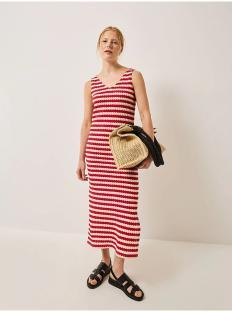 Woman in red and white striped midi dress and black sandals holding a straw tote bag.