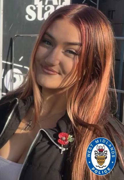 Portrait of Liberty Charris with long reddish-brown hair, wearing a black jacket with a poppy pin.