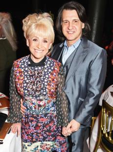 a woman in a floral dress stands next to a man in a suit