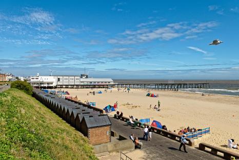 Claremont Pier and beach in Lowestoft, Suffolk, with people enjoying a sunny day.