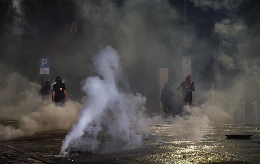 Police and protesters obscured by tear gas during a protest against the Israeli football team.