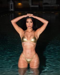 Kim Kardashian in a gold bikini in a pool.