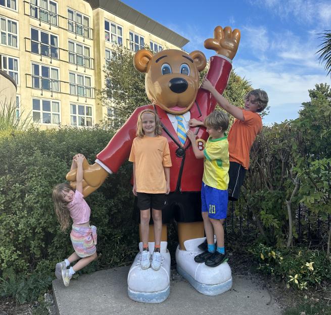 Children playing on a large bear statue.