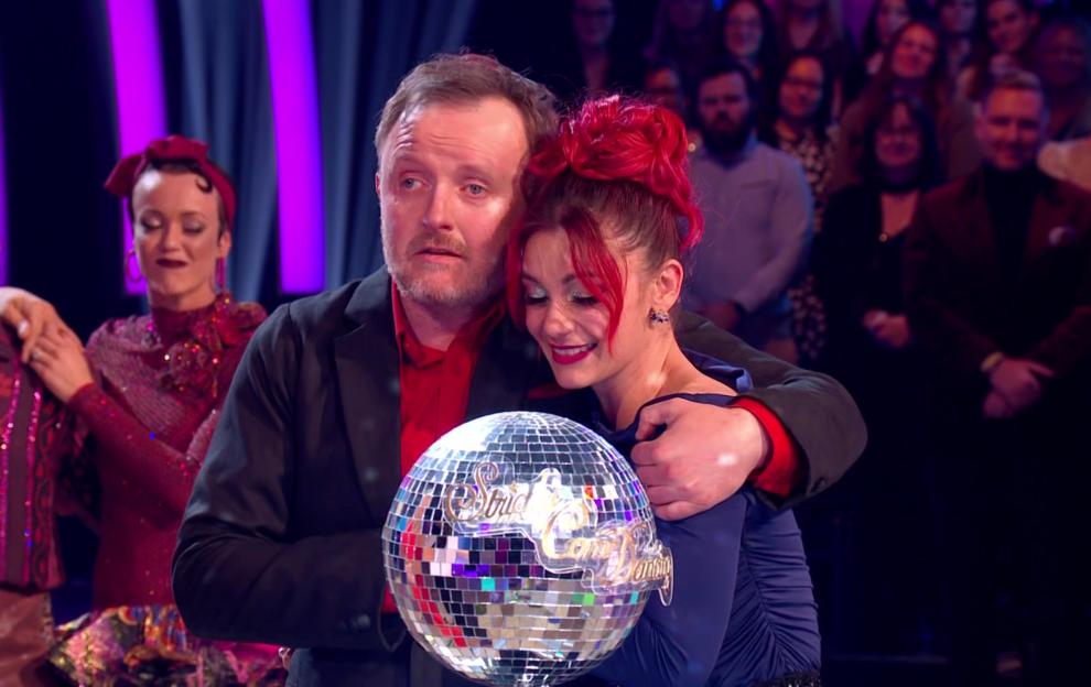 Chris McCausland and Dianne Buswell holding the Glitterball Trophy after winning Strictly Come Dancing.