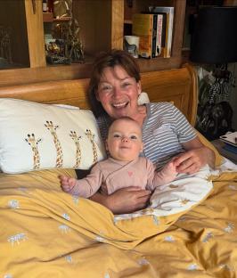 Woman and baby in bed under yellow tiger-print bedding.