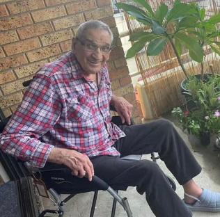 Smiling man in a wheelchair outdoors.