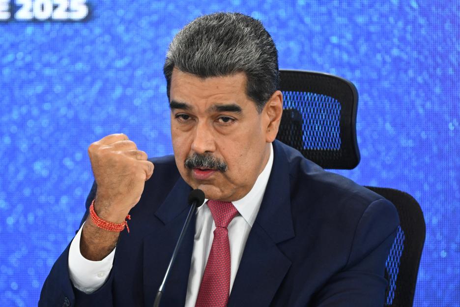Venezuelan President Nicolas Maduro speaks at a microphone with a clenched fist.