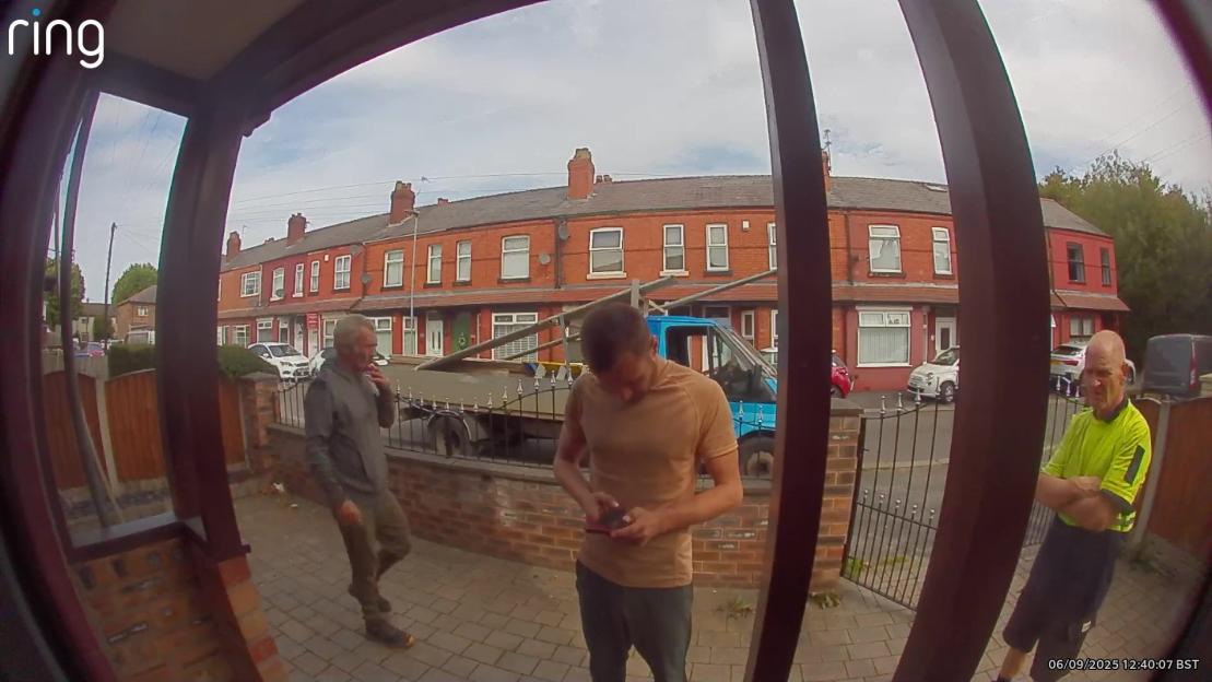 Ring doorbell camera footage of three construction workers setting up scaffolding outside a house.