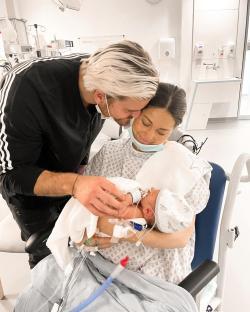 Parents holding their newborn baby in a hospital.