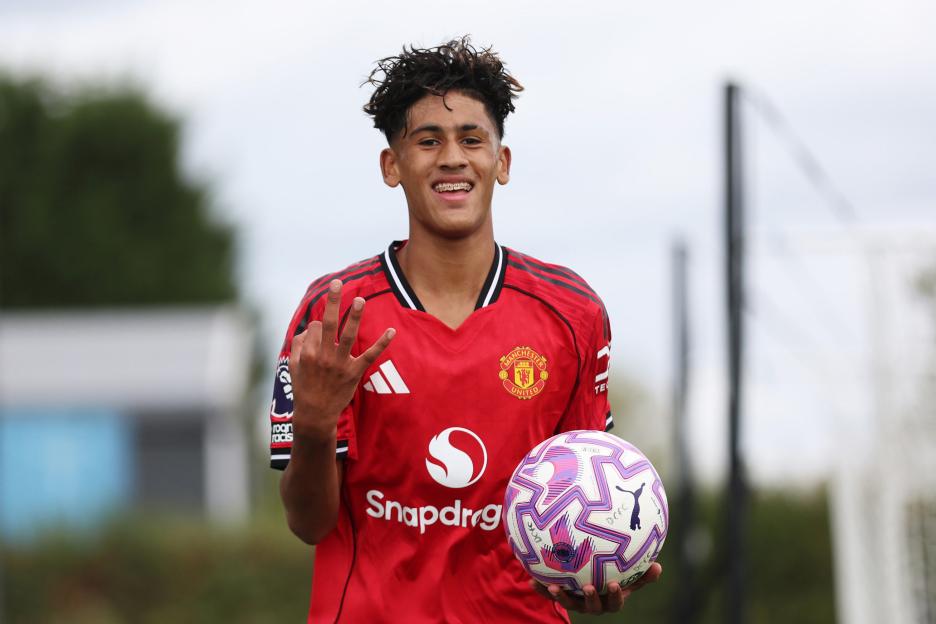 JJ Gabriel of Manchester United celebrates a goal by holding a soccer ball and making a hand gesture.
