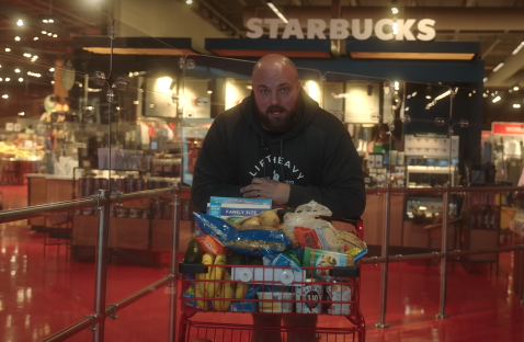 Man with full shopping cart in grocery store.