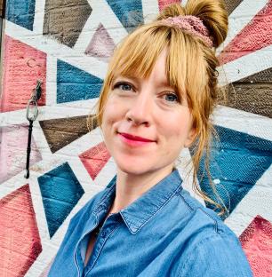 Woman in denim shirt in front of geometric mural.