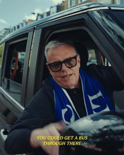 Man in a car wearing a Chelsea scarf.