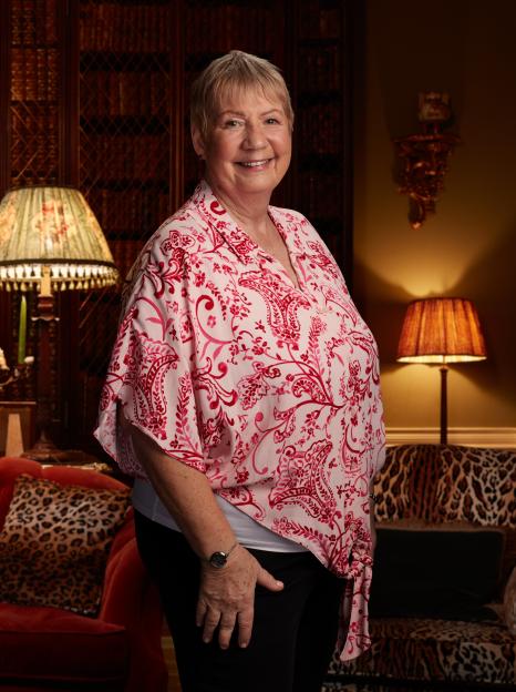 Portrait of a smiling woman in a pink floral blouse.