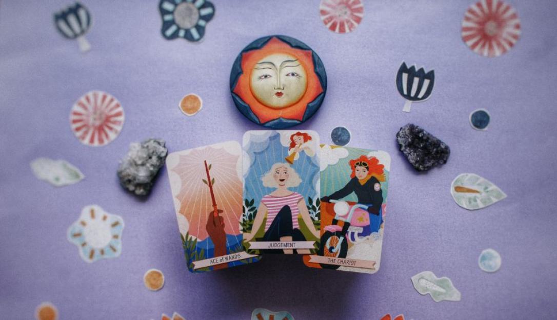 Illustration of three tarot cards: Ace of Wands, Judgement, and The Chariot, arranged around a sun face.