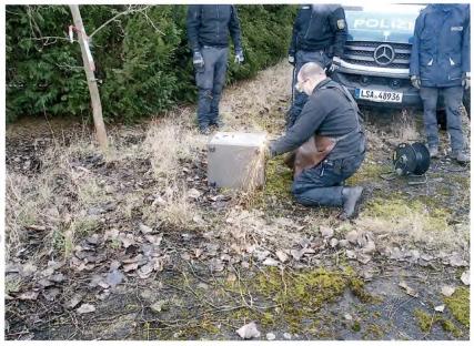 Police officers cutting open a metal box.