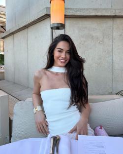 Woman in white top sitting outdoors at a restaurant.