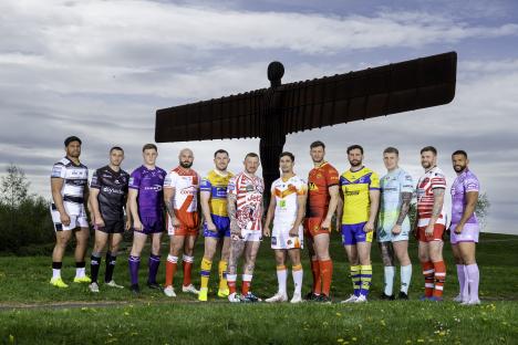 Rugby players in various team jerseys posing in front of the Angel of the North.