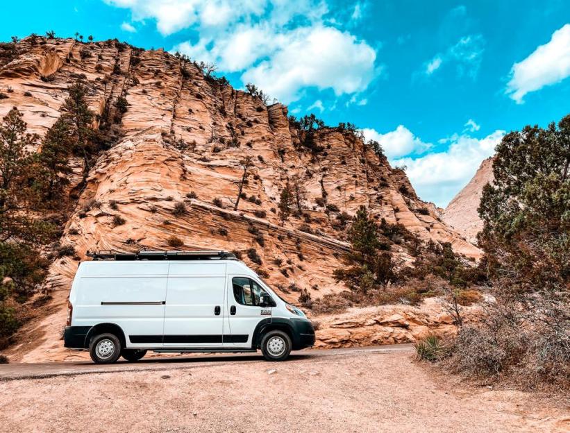 White van parked near a sandstone cliff.