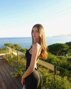 Woman in black dress overlooking ocean.