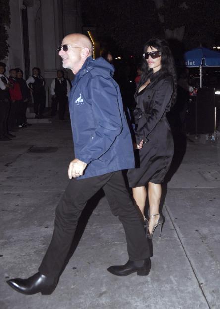 Jeff Bezos and Lauren Sanchez walking at night, Sanchez in a black trench coat and Bezos in a blue jacket.
