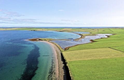 Aerial view of a Scottish beach and surrounding farmland for sale.