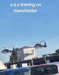 Two helicopters flying over a parking lot.