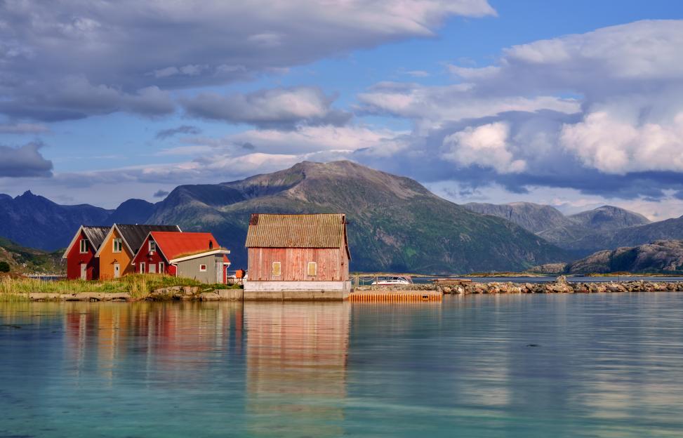 Colorful wooden huts on Sommaroy Island, Norway, with mountains in the background.
