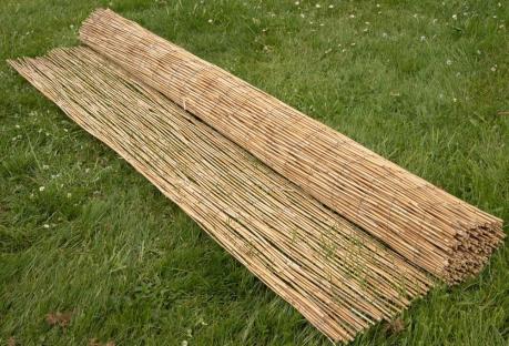Rolled-up reed fencing on the grass.