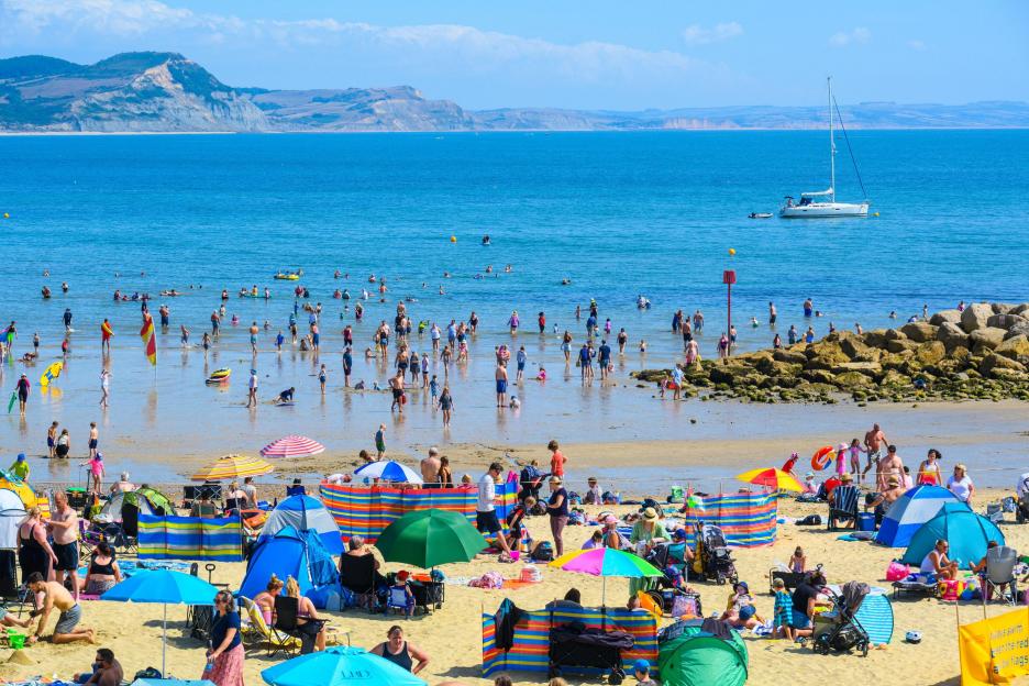 Crowded beach with many sunbathers and holidaymakers.