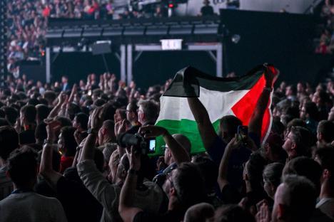 A person raises a Palestinian flag at a concert.
