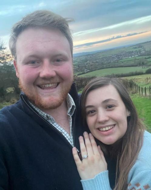 Engaged couple posing outdoors.