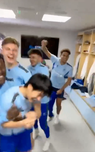 Screenshot of a group of soccer players celebrating in a locker room.
