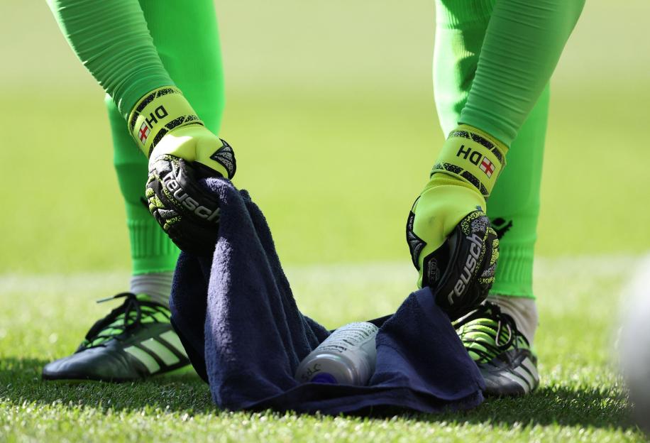 Dean Henderson of Crystal Palace checking notes on his drinks bottle during a penalty shootout.