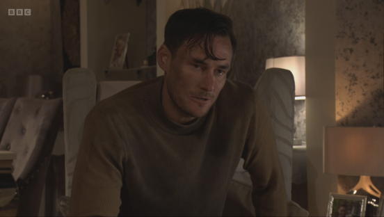 Screenshot of a man sitting in a chair, looking distressed.