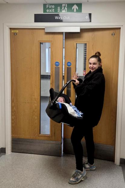 Megan Isherwood leaving the hospital with baby Jackson in a carrier.