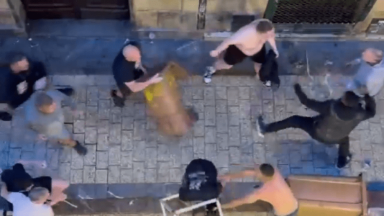 A group of people fighting on a cobblestone street.