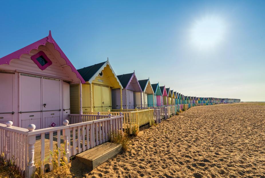 Pastel-colored beach huts on a sandy beach.