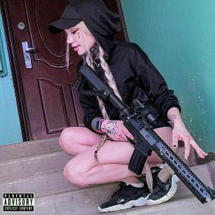 Woman with blonde hair and tattoos crouching with a rifle.
