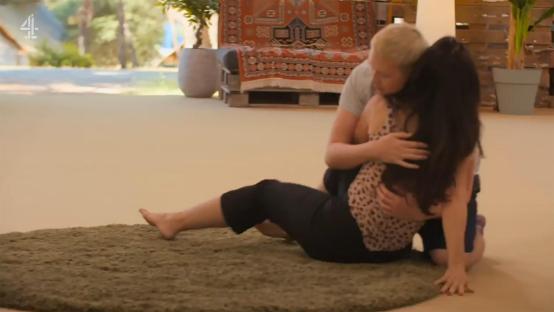 A woman embracing another woman on the floor.