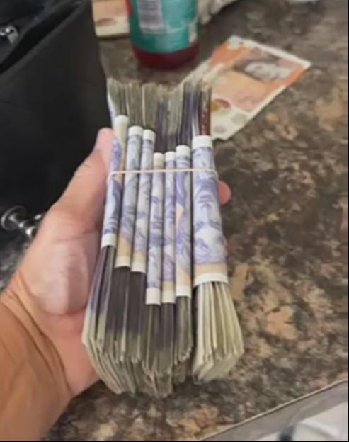 A hand holding a large stack of cash.