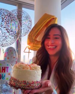 Woman holding a birthday cake with a sparkler.