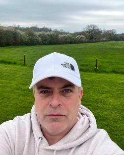Simon Gregson, actor who plays Steve McDonald in Coronation Street, wearing a white The North Face baseball cap.