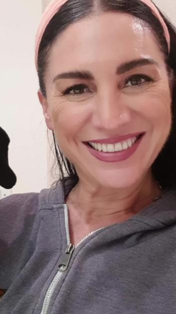 A woman smiling in a gray hooded sweatshirt.