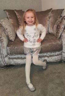Young girl wearing a sparkly silver outfit.