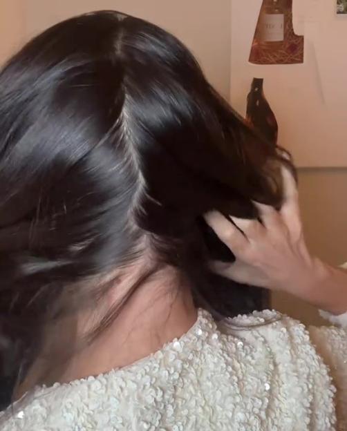 Woman showcasing hair extensions on the back of her head, wearing a white sequined top.
